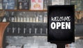 Come in WeÃ¢â¬â¢re OpenÃ¢â¬â¢ on cafe waiter standing in front of coffee shop vintage Royalty Free Stock Photo